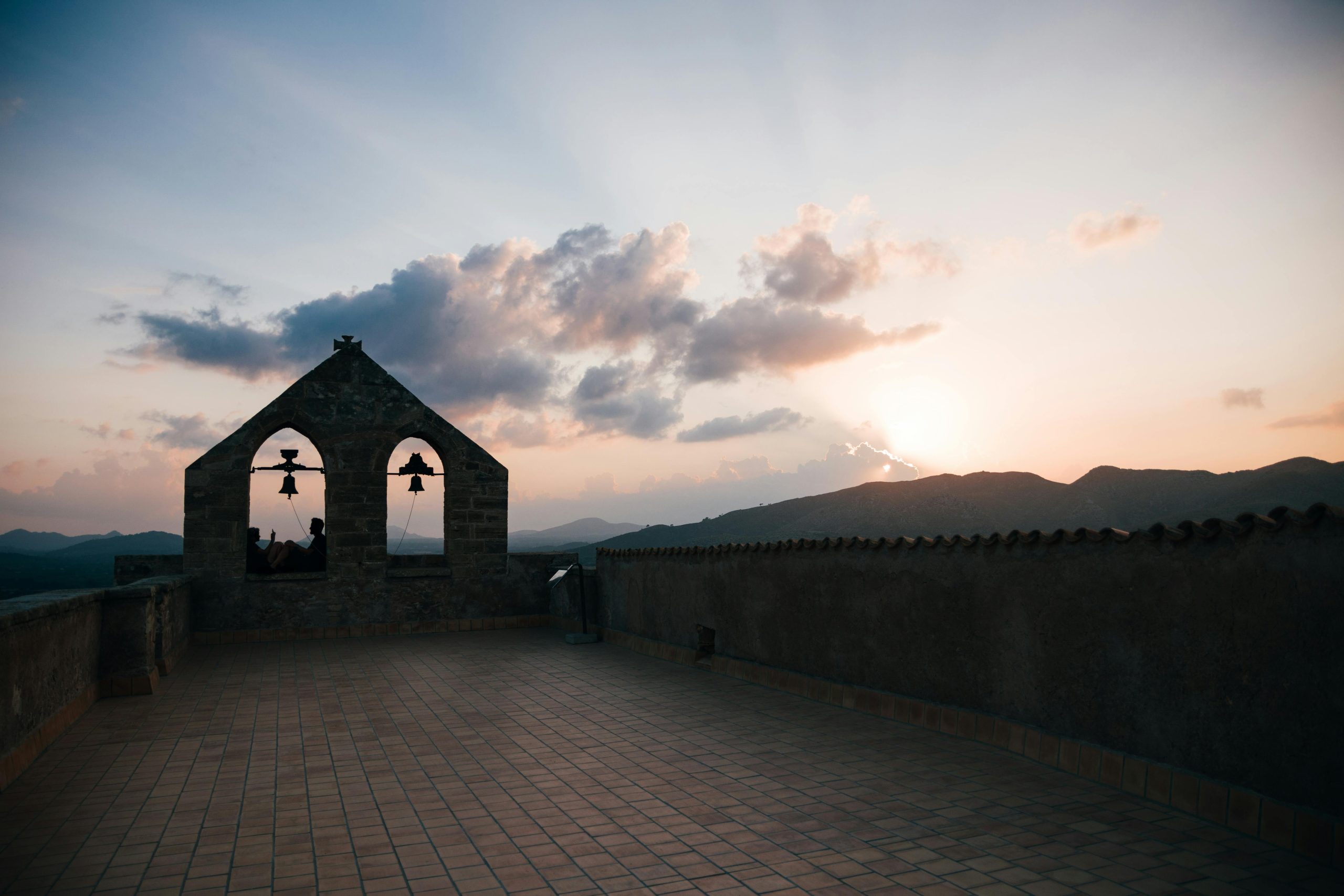 Silhouette of a monastery bell tower during a stunning sunset with mountain views.