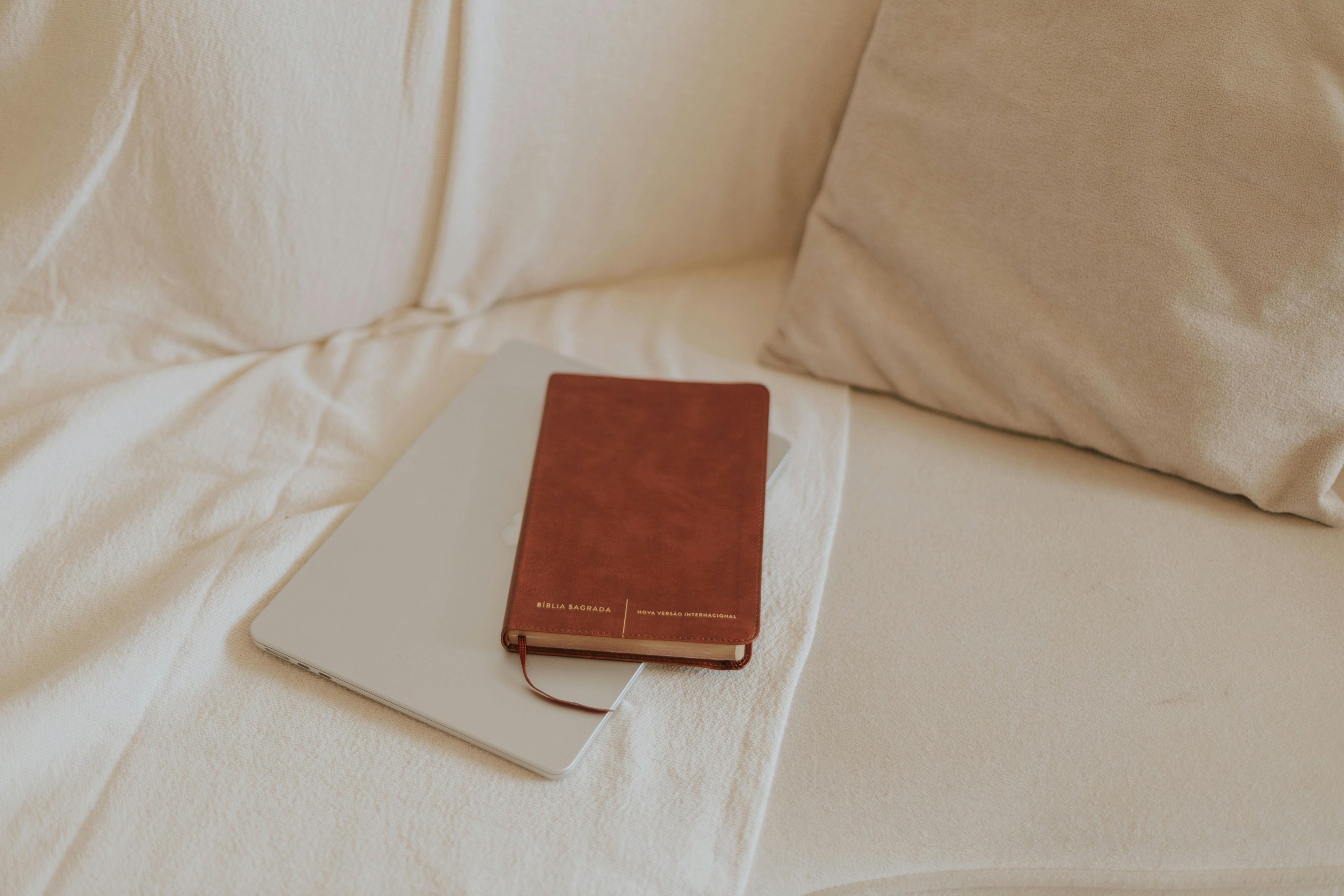 A Bible rests on a tablet on a cozy beige sofa, creating a serene devotional setting.