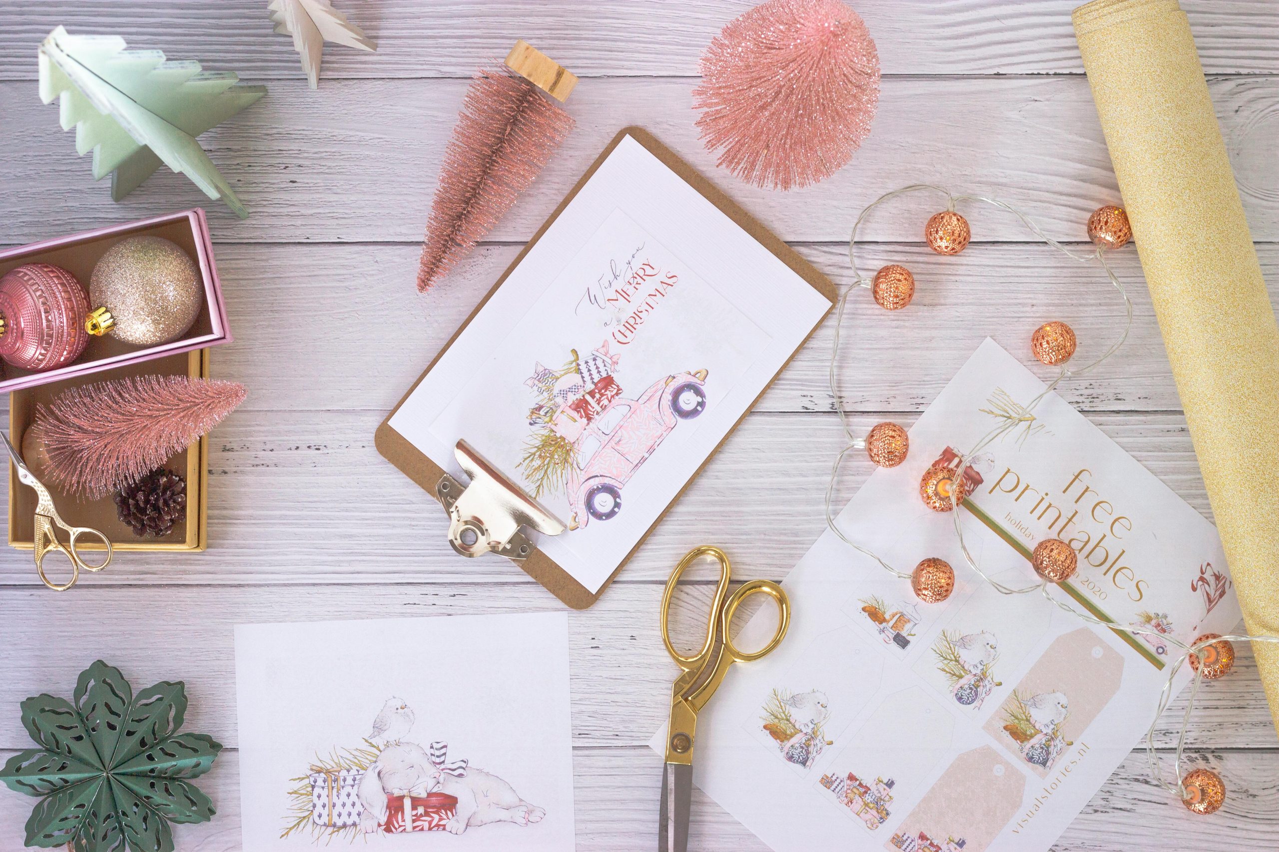 Flat lay of festive pastel holiday crafting materials including cards, ornaments, and gift wrap.
